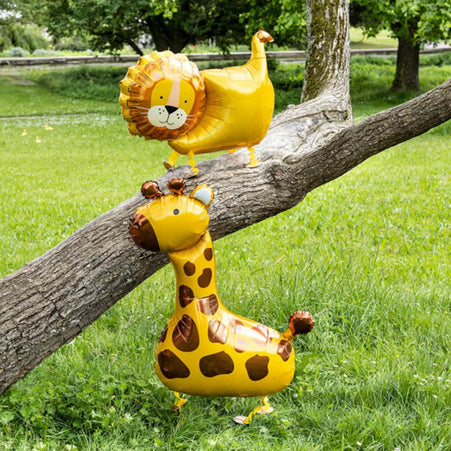 Laufende Airwalker Ballons Löwe und Giraffe an einem Baumstamm auf einer grünen Wiese